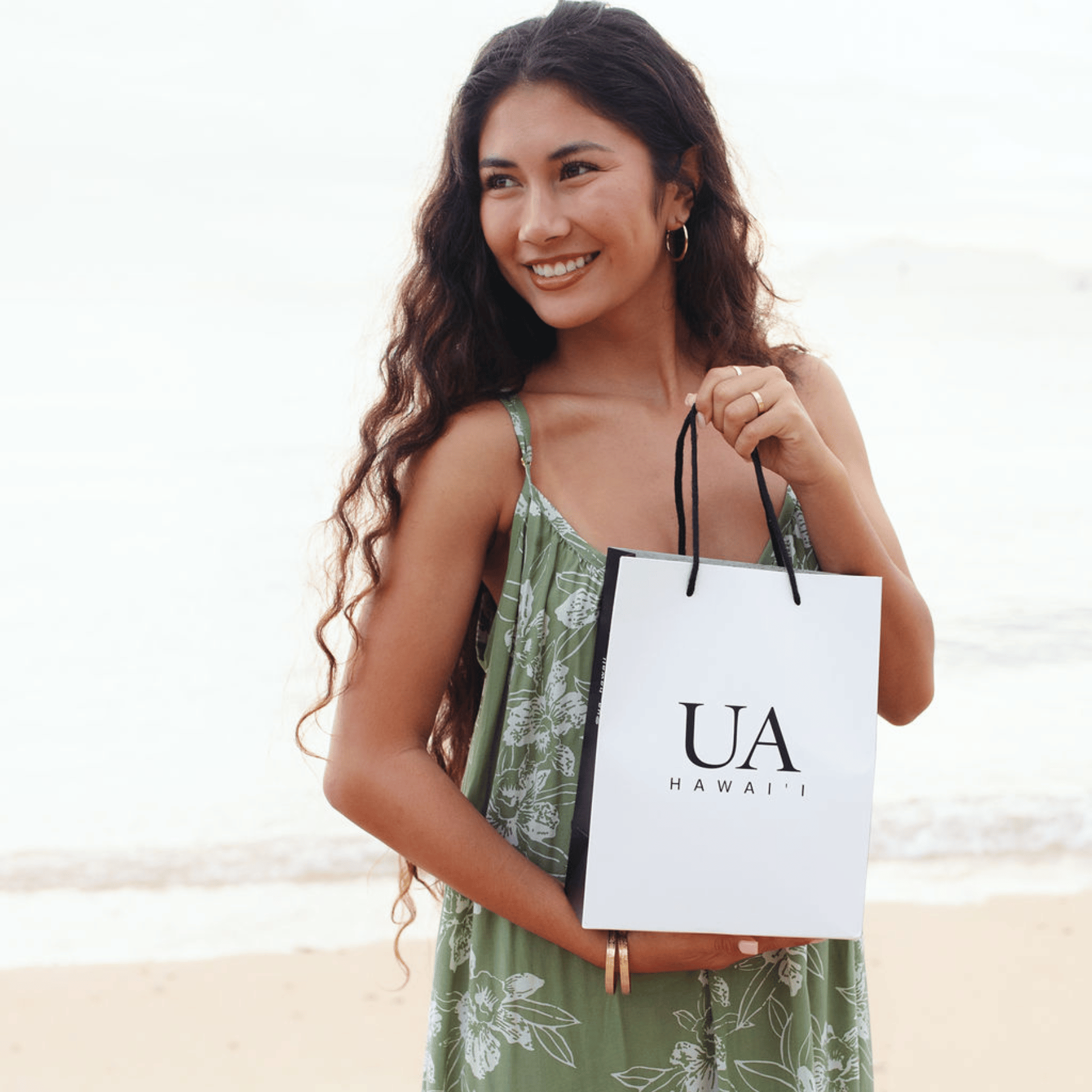 Woman on beach holding Ua Hawaii gift bag