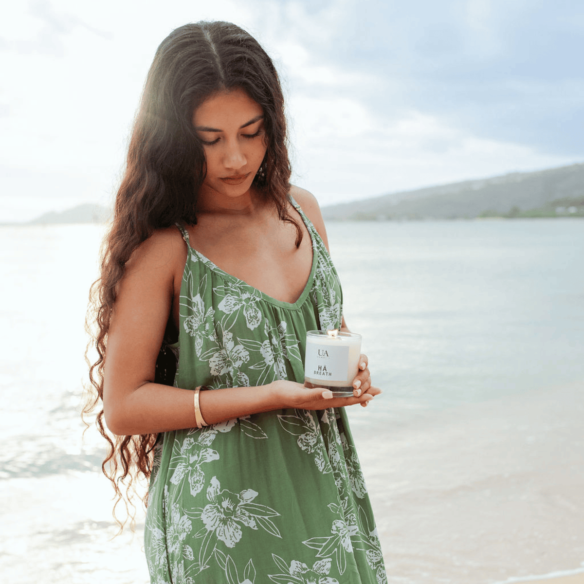 Woman on beach looking down and holding Hawaiian candle