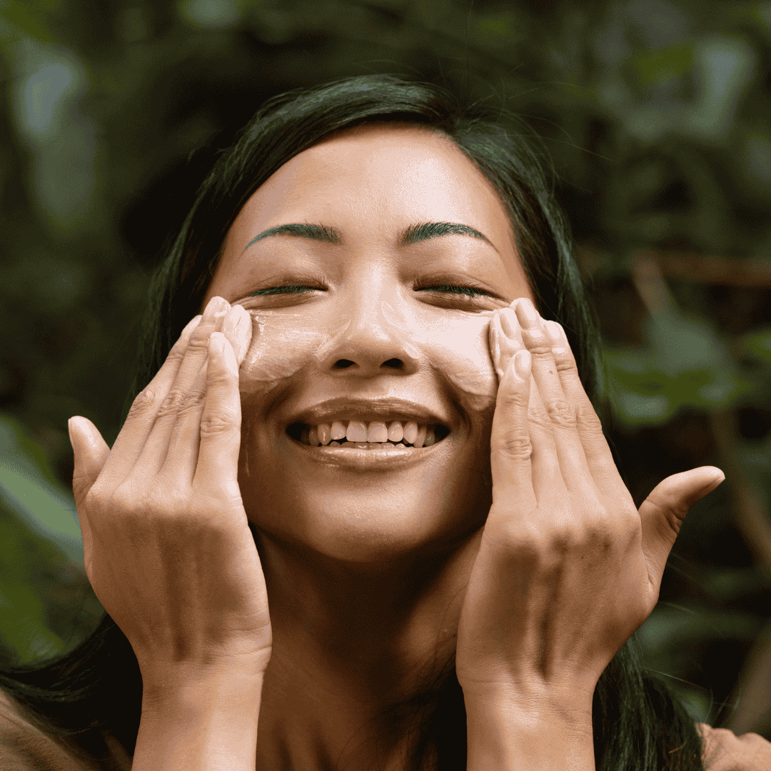 Woman rubbing facial cleanser on her face while smiling