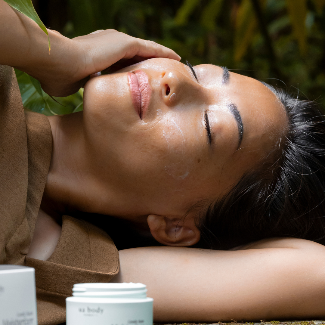 Woman lying down and rubbing moisturizer into her face